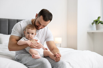 Father with his little baby on bed at home. Space for text