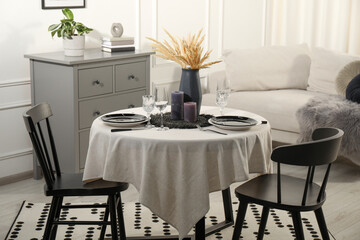 Stylish table setting with beautiful dishware and black chairs in dining room