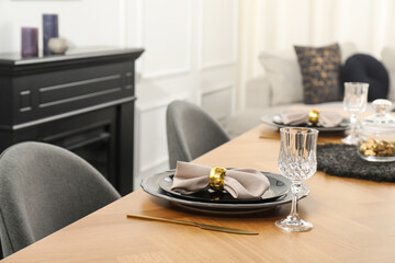 Stylish table setting with black dishware in dining room