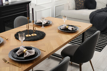 Stylish table setting with black dishware in dining room