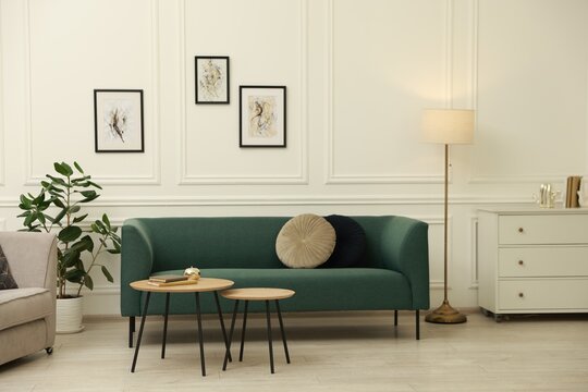 Stylish living room interior. Comfortable sofa, chest of drawers and nesting tables indoors