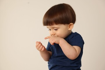 Portrait of cute little boy on light grey background. Space for text