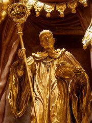 Obraz premium Golden statue of a saint holding a staff and dish in a historic church