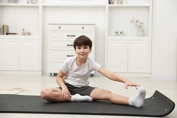 Fototapeta premium Boy doing exercise on fitness mat at home. Sport activity