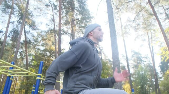 Man doing high knee jumps in outdoor gym, trees in background. Healthy lifestyle. Fitness training