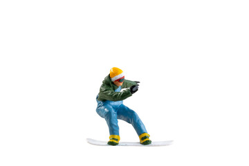 Miniature figurine depicting a snowboarder in mid-motion isolate on white background with clipping...