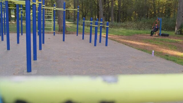 Man with pained expression during sit-up at outdoor gym. Tired and struggling. Workout in the park