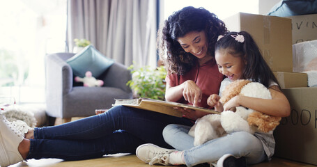Memory, mother and kid with photo album in new home for moving in, nostalgia and pointing to old house. Happy, woman and girl child on floor with pictures for unpacking, bonding together or milestone