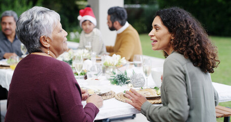 Christmas, dinner and women with talking by home for bonding, festive celebration or social gathering. Happy family, people and conversation together on patio with food, holiday lunch or relationship