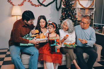 Portrait of Asian family exchanging presents during christmas at home. Attractive happy people holding gift box, celebrate holiday thanksgiving, xmas eve tradition in living room in house together.