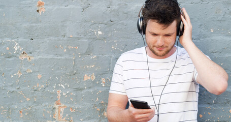 Man, headphones and phone with music on wall background for audio streaming or sound track. Male...