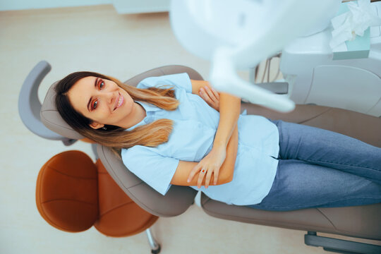 Happy Smiling Patient Sitting on the Chair at the Dentist. Carefree relaxed woman sitting in a dental cabinet 

