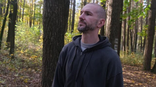 A man walks in an autumn forest. Side view. Sunlight shines through trees