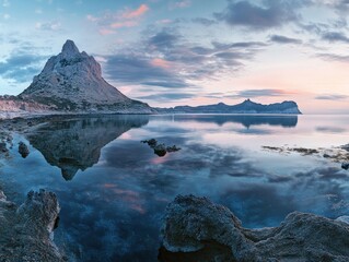 Serene sunrise over calm sea reflecting majestic mountains.