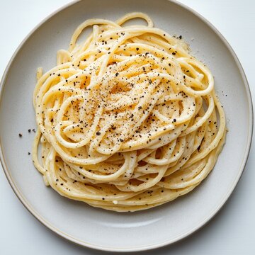 Delicious Italian cacio e pepe pasta dish. Spaghetti tossed with creamy cheese sauce, black pepper. Plate of pasta presented beautifully. Authentic Italian food. Traditional homemade meal. Culinary
