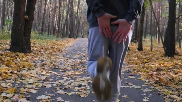 A sporty man is doing leg exercise in the autumn woods