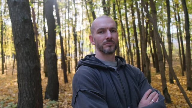 Portrait of a man in hooded jacket in fall woods. Serious look