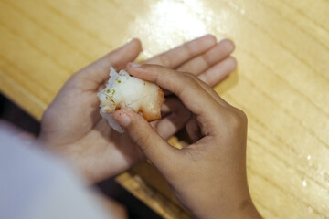 close up of a child's hand holding sushi