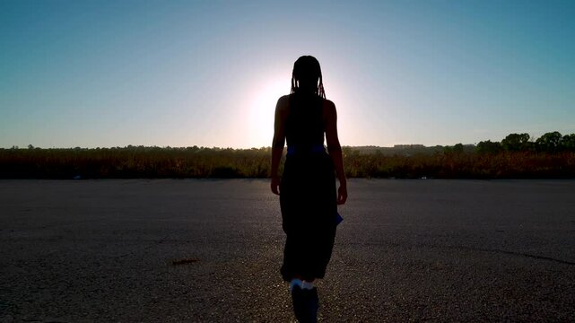 Chica camina hacia el atardecer por una pista de aterrizaje, se para y realiza movimientos de danza oriental para m&uacute;ltiples conceptos.