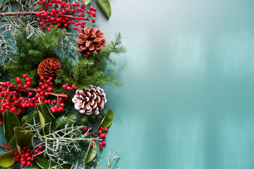 Winter green leaves and berries composition on green background. Winter and Christmas decoration background. Natural elements design for Merry Christmas and Holiday.