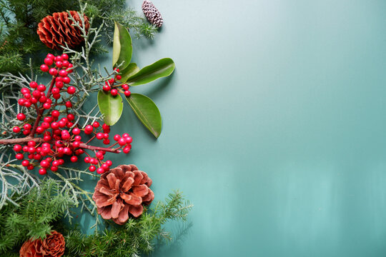 Winter green leaves and berries composition on green background. Winter and Christmas decoration background. Natural elements design for Merry Christmas and Holiday.