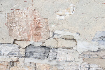 An old bricks background with different kind of stone. A close-up of an old and damaged wall. Ancient architecture and material for the construction of exterior wall. Gray and stone background.