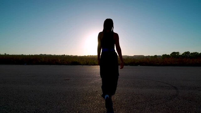 Chica camina hacia el atardecer por una pista de aterrizaje, se gira hacia la c&aacute;mara y realiza movimientos de danza oriental para m&uacute;ltiples conceptos.