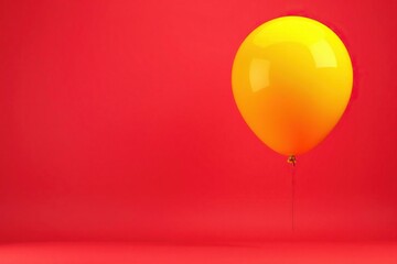 Bright yellow balloon floating above a vibrant red background, helium filled, buoyant