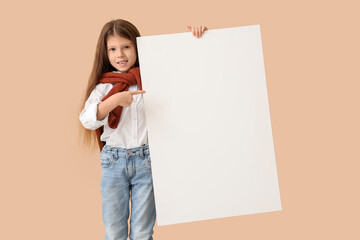 Cute little girl pointing at blank poster on beige background. Opposite Day celebration