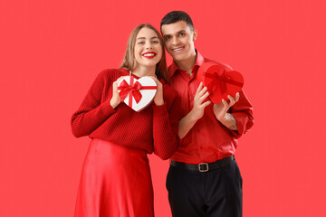 Young couple in love with gifts on red background. Valentine's Day celebration