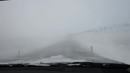 Inside car view of driving during extreme weather during winter snowing in Iceland