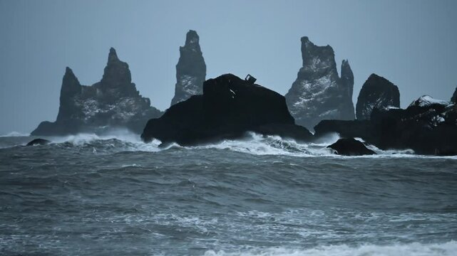 Panoramic view of basalt sea stacks Reynisdrangar from black sand beach Reynisfjara, Iceland