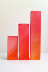 Three gradient red and orange rectangular blocks of varying heights set against a neutral background, showcasing modern minimalistic design.