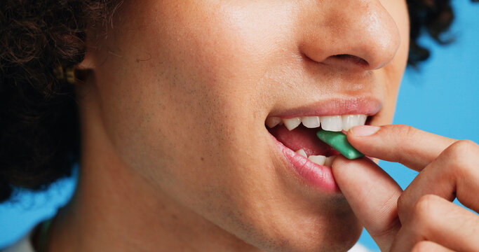 Chewing gum, dental and closeup of person in studio for fresh breath, oral hygiene or candy. Cleaning, mint sweets or bubblegum with snack and mouth on blue background for teeth care and eating