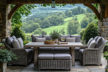 Fototapeta premium Stylish light gray rattan sofa and dining table set with matching footstool, placed on spacious garden patio with green trees and grassy fields in the background.
