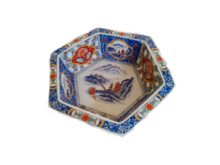 A hexagonal ceramic bowl with colorful floral and landscape patterns.

