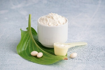 Cup and scoop of collagen powder and pills on white grunge background