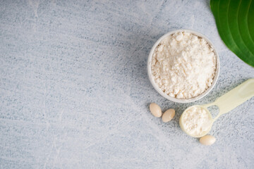 Cup and scoop of collagen powder and pills on white grunge background