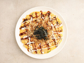 Okonomiyaki with mayonnaise drizzle, barbeque sauce , dried katshuoboshi and green laver on white plate