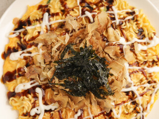 Okonomiyaki with mayonnaise drizzle, barbeque sauce , dried katshuoboshi and green laver on white plate