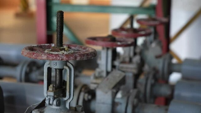 old cast iron industrial shut-off valves. Pipes, shut-off valves and pumps of the heating and hot water supply system in an industrial boiler room. Heating and water supply system