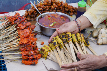 Close-up of traditional pork satay skewers being grilled over hot charcoal, showcasing authentic...