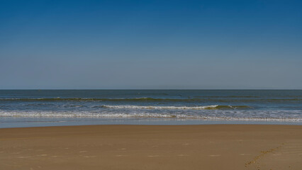Endless turquoise ocean. The waves roll towards the shore, foam and spread over the sandy beach. Clear blue sky. Copy Space. Madagascar. Morondava. Mozambique Channel