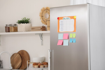 Fridge with sticky notes and meal plan in modern kitchen