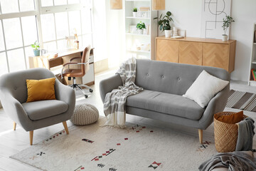 Interior of light living room with sofa, armchair and workplace