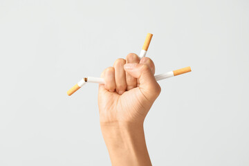 Female fist with broken cigarettes on grey background. Stop smoking concept