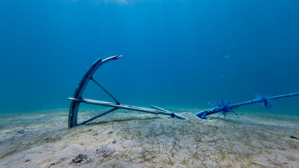 Anchor on the seabed. A ship's anchor lies on a sandy bottom in clear transparent water. © Houston