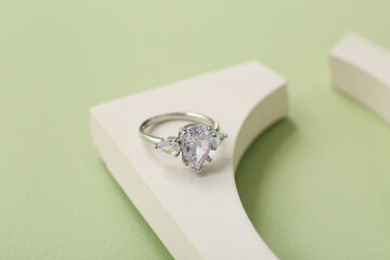 Podium with stylish diamond ring on green background