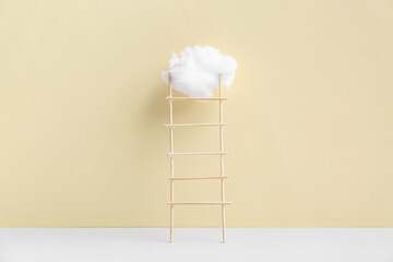 Ladder with cotton cloud on beige background