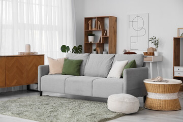 Interior of modern living room with grey sofa, pouf and coffee table